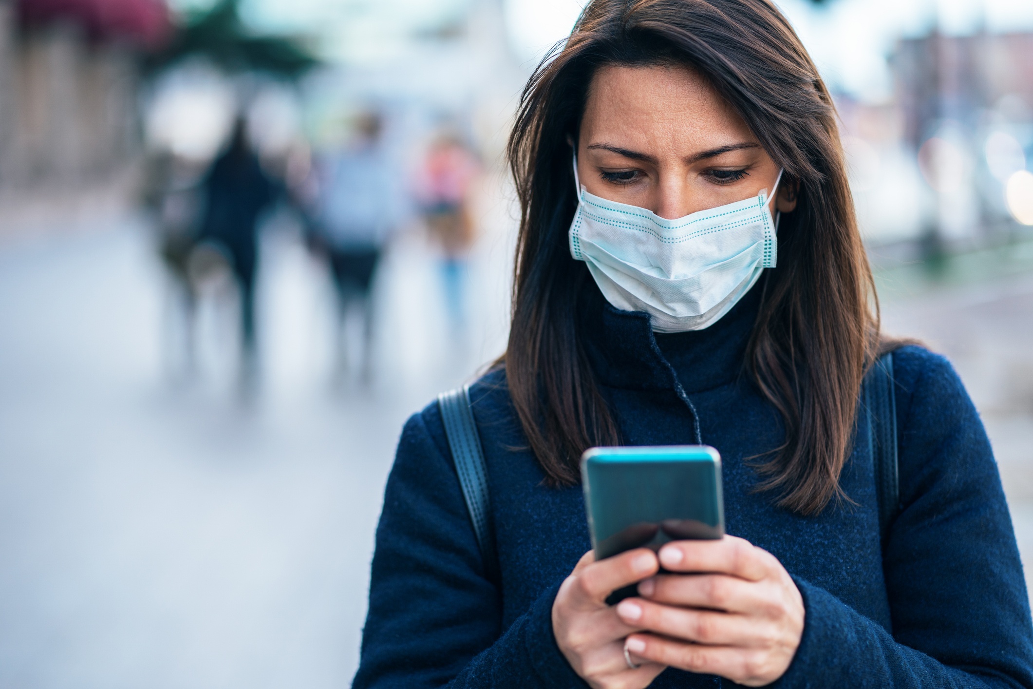 woman in mask checking her smartphone